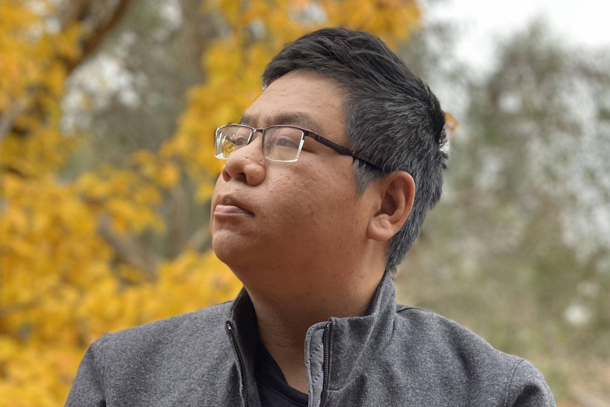 Minh Nguyen Thanh sitting on a wall in front of a sign for the Australian National University