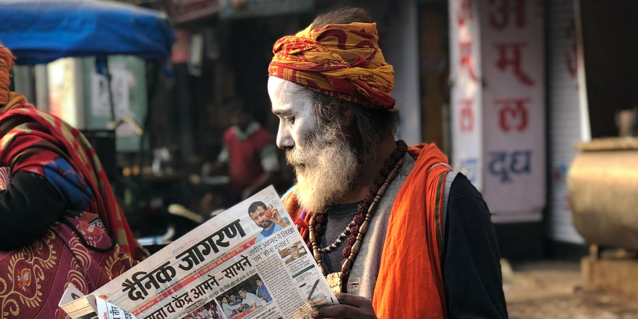 Man reading newspaper beside street 