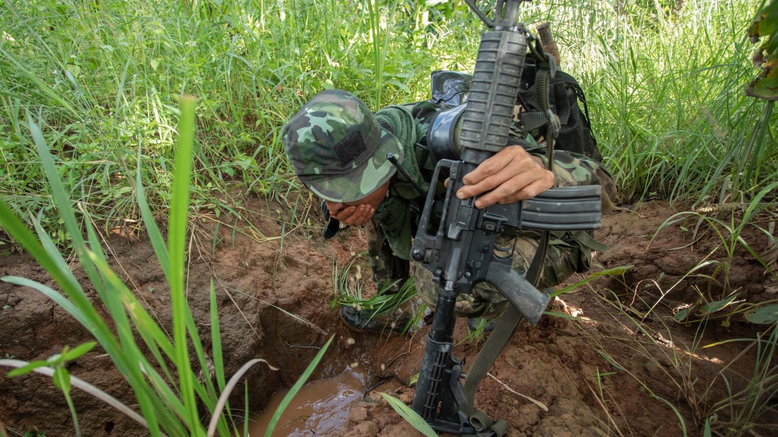 Myanmar Update 2023: 'How to quantify FEAR?' art exhibition A soldier holding a gun crouching in the grass with his face obscured by his helmet