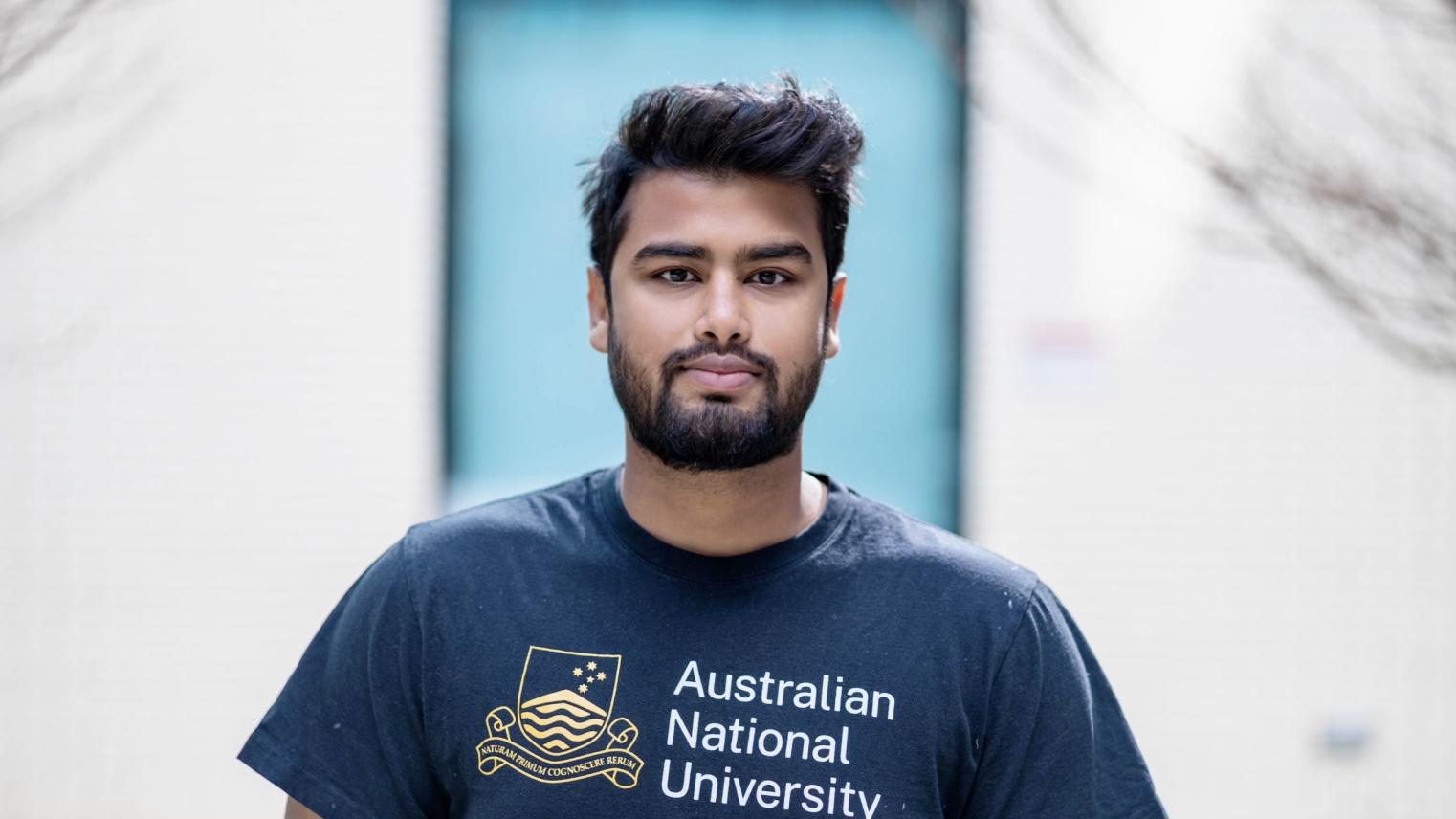 Sai Hossain Student Sai Hossain looking at camera wearing an ANU shirt